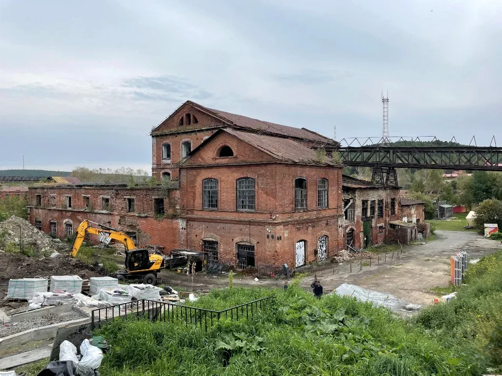 Старый кирпичный корпус завода и экскаватор во дворе