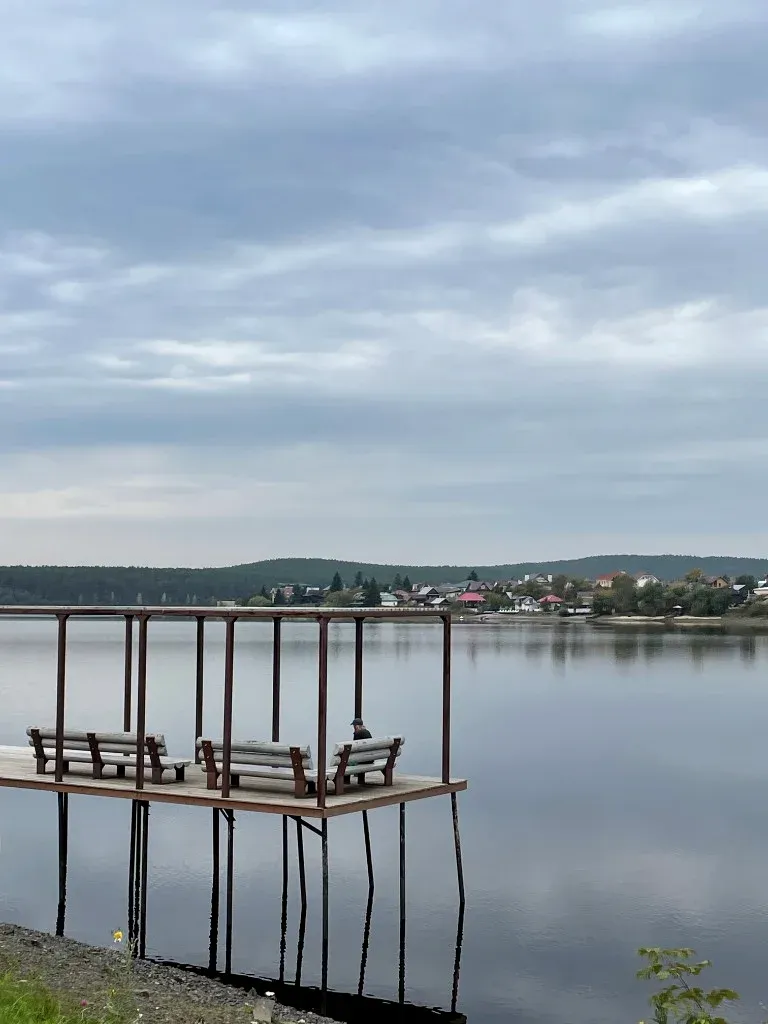 Пустой пирс со скамейками на пруду